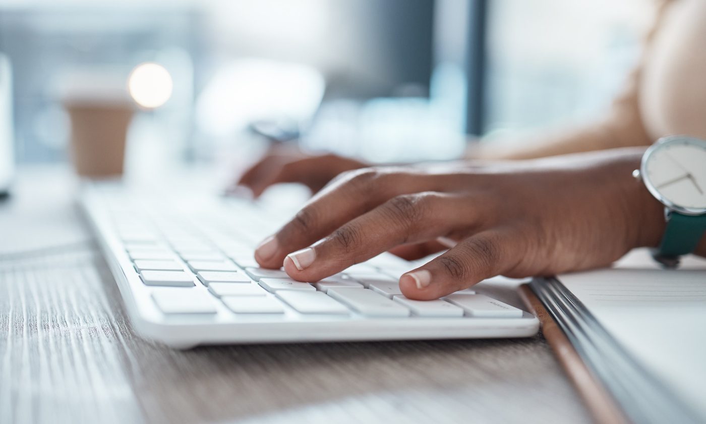 Manos escribiendo en el teclado de un ordenador en una oficina